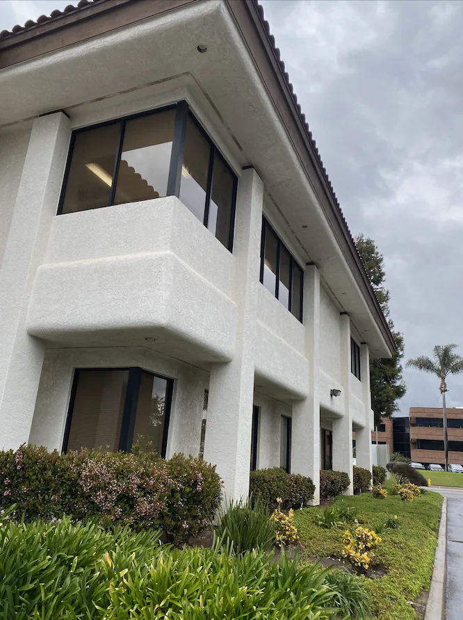 Carlsbad office building with heavy dated stucco texture and brown trim before refinishing