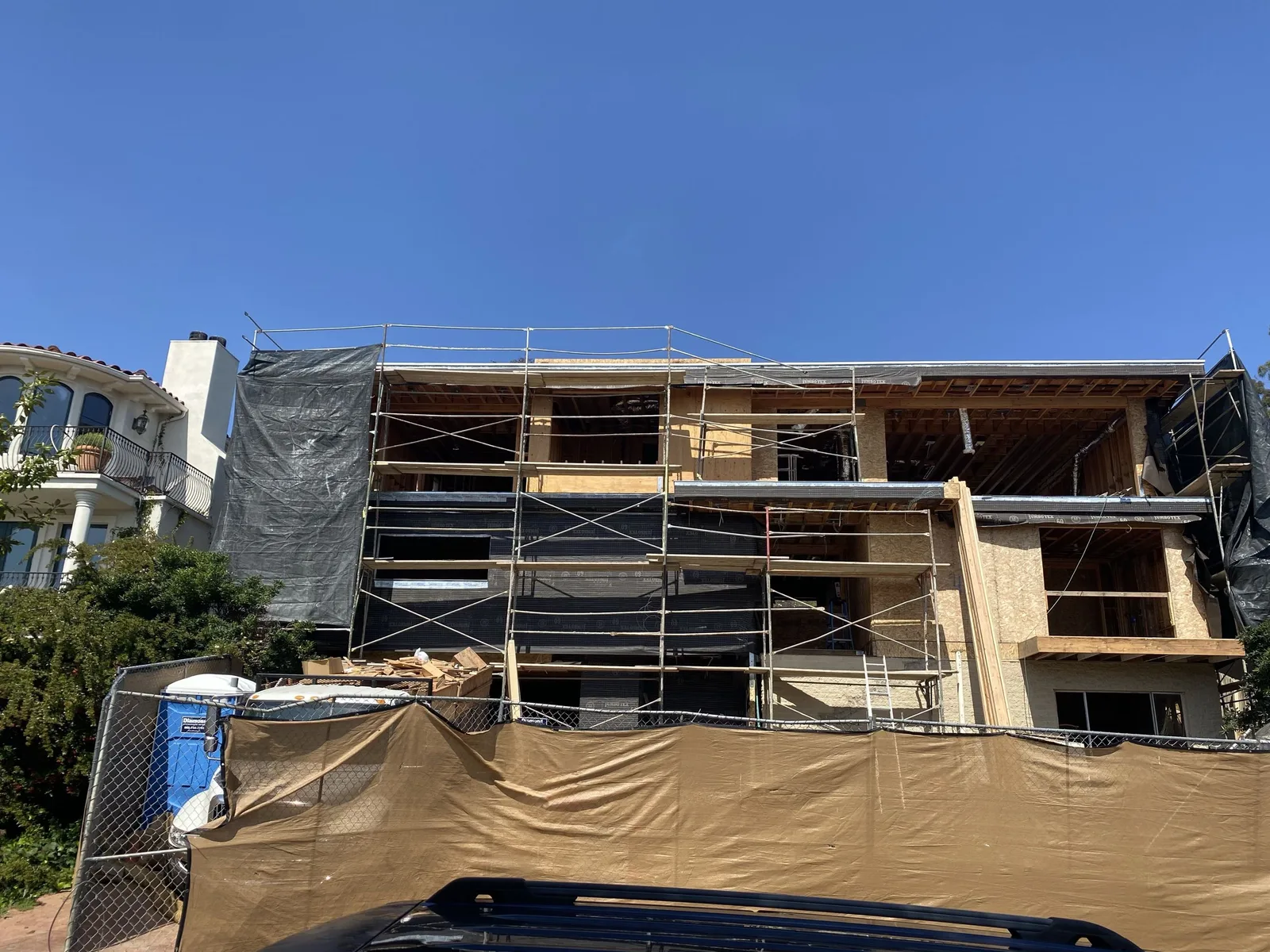 Hillside home in La Jolla under construction with scaffolding and weather-resistive barrier before stucco