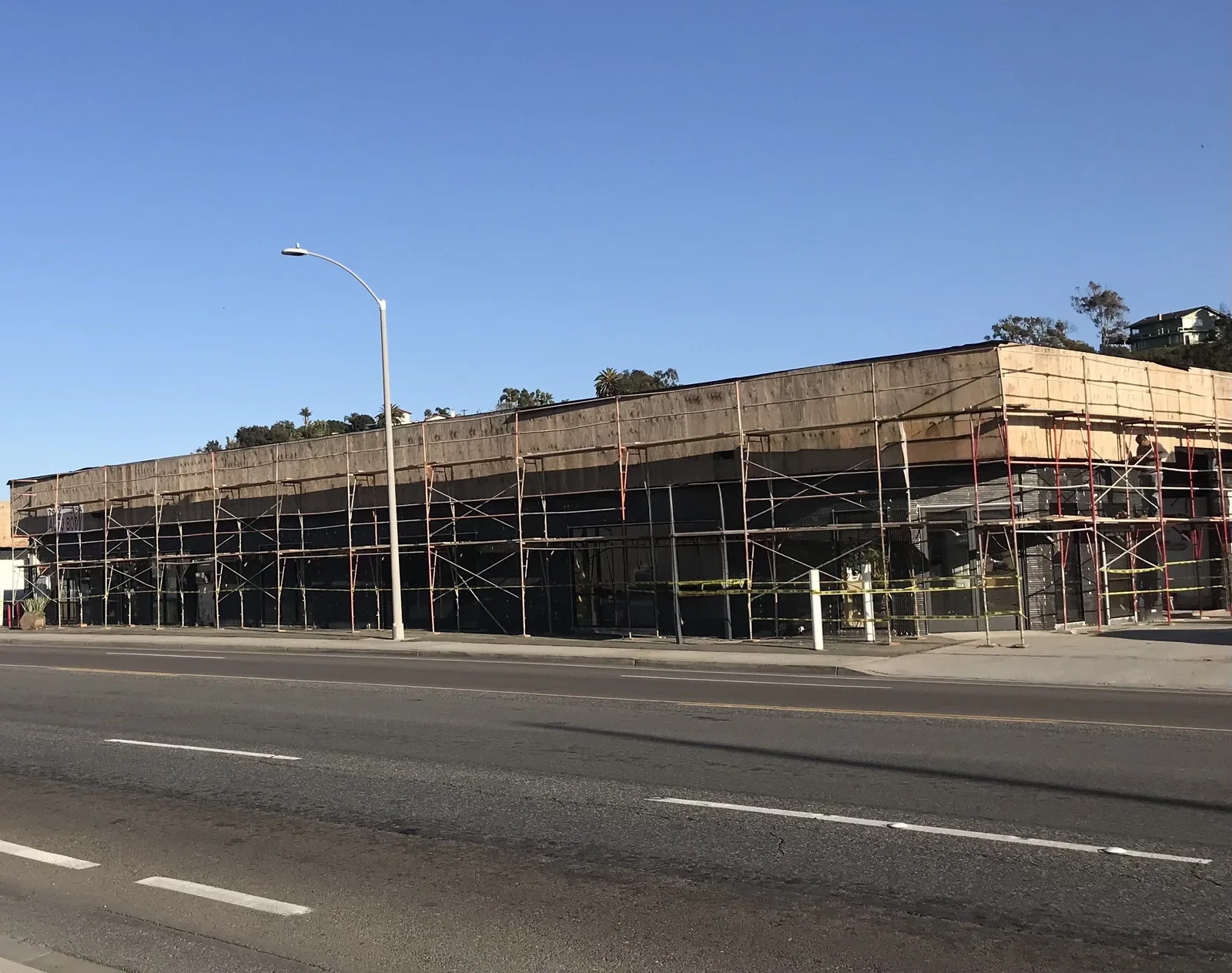 Commercial auto body building in Oceanside scaffolded for lath and plaster repair and refinishing