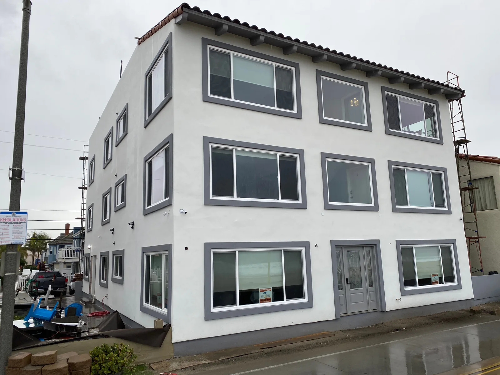 Refinished white stucco exterior with grey trim bands on a Pacific Beach building by Maya Stucco Inc.