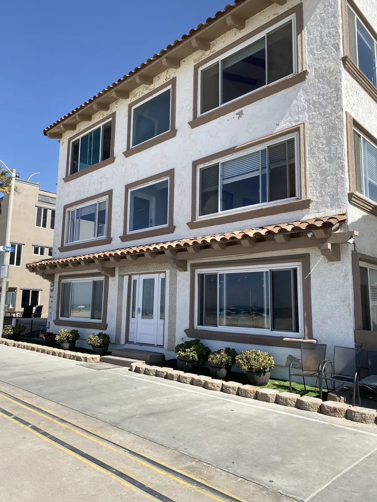 Close view of failing stucco and peeling finish on a coastal building in Pacific Beach
